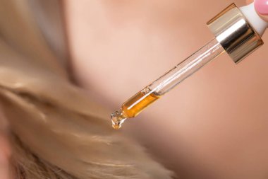 Yakından çekilen bir görüntü, bir damlatıcıyı ustalıkla yakalıyor ve uygun ve etkili saç bakımı için besleyici saç yağı salıyor.