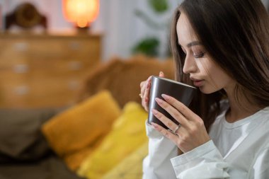 Huzurlu ve huzurlu bir sahne. Huzurlu bir ortamda sıcak bir içeceğin tadını çıkaran bir kadın.