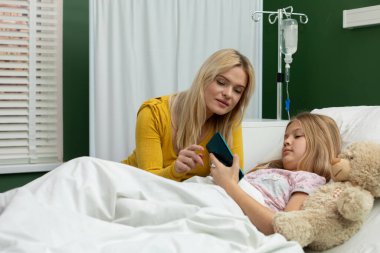 Yürekten bir hastane anında, bir kadın ve bir kız aynı telefonu paylaşıyor, zor bir zamanda bağlantılarını güçlendiriyor.