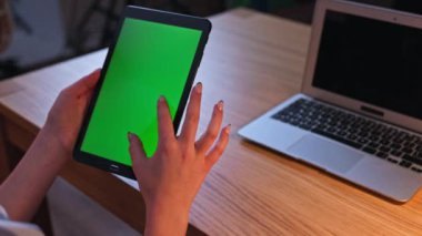 Bir kişi, ortam ve tasarım uygulamaları için ideal yeşil ekran gösteren bir tabletle etkileşim kurar.