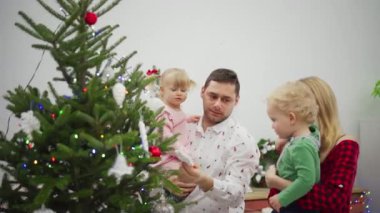 Çocuklarla birlikte Noel ağacını süsleyen bir aileyi yakalayan keyifli ve neşeli bir an.