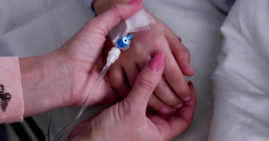 Bir çocuk, tedavi ve tedaviyi temsil eden tıbbi bir ortamda damar içi damar içi damarına nazikçe bağlanır.