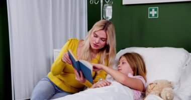 İlgili bir yetişkin, bir çocuğa hastane odasında kitap okur. İyileşme sürecinde rahatlık ve arkadaşlık sağlar..