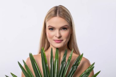 Uzun saçlı çarpıcı bir manken canlı yeşil bitkiler barındırır. Güzelce vücut bulmuş doğa ve ahenk.