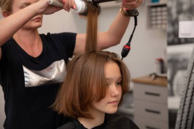 Yetenekli bir stilist, moda ve modaya uygun bir saç stili yaratmak için saç maşası kullanır.