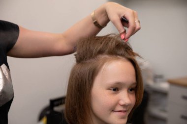 Yetenekli bir kuaför, şık bir kuaförde modern ve modaya uygun bir saç stili yaratıyor.