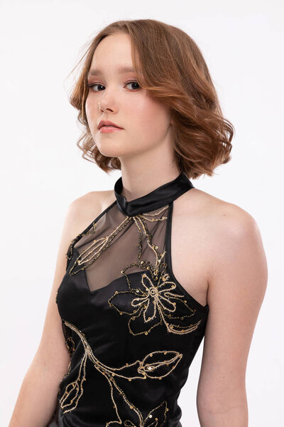 A stylish model elegantly poses in a chic black dress that showcases intricate and beautiful floral patterns