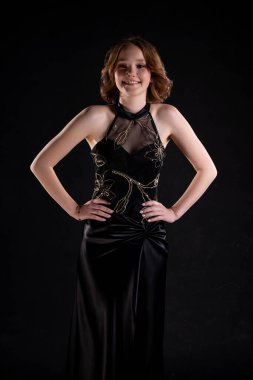 Dengeli ve zarif bir model, çok güzel bir şekilde siyah bir gece elbisesi sergiliyor.