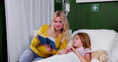 Bir hastane ortamında, şefkatli bir kişi genç bir kıza sıcak bir hikaye okur, derin bir sıcaklık ve destek iletir.