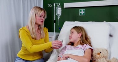 Bir hastane odasında, kendini adamış ve sevgi dolu bir anne şefkatle hasta, hasta çocuğuna bakar.