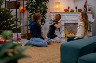 Üç yakın arkadaşın sıcak şöminenin yanında neşeli bir atmosferin keyfini çıkardığı gerçekten iç açıcı bir sahne.