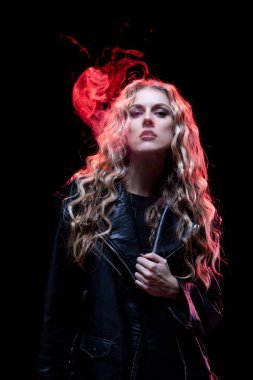 Canlı duman efektleri ve dramatik ışıklandırmayla vurgulanmış deri ceketli bir kadının büyüleyici portresi.