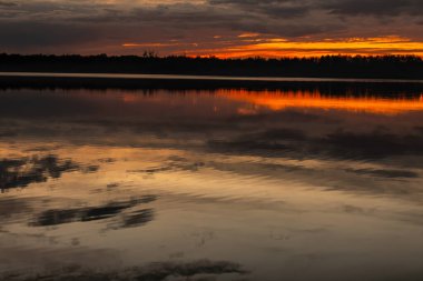 Şok edici bir günbatımı sakin suları, canlı renkleri ve doğanın dingin güzelliğini yansıtır.