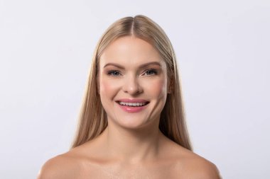 Uzun, dalgalı sarı saçlı neşeli bir kadın neşeyle parıldıyor, doğal güzelliğini ve kendine olan güvenini gösteriyor.