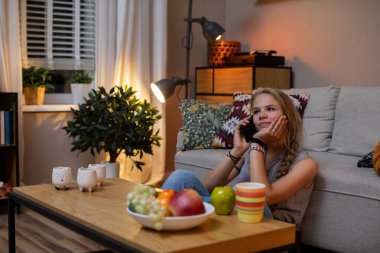 Bir dizi meyveyle çevrili bir telefon görüşmesi yapan bir kadını gösteren samimi ve davetkar bir akşam sahnesi.