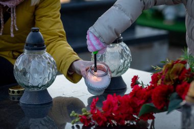 İnsanlar bir mezarlıkta toplandı, sevdiklerini onurlandırmak ve hatırlamak için mum yaktılar.