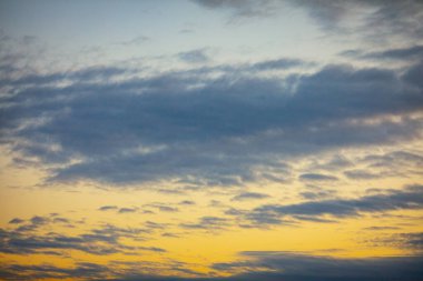 Sakin ve huzurlu bir gökyüzü yumuşak bulutlarla dolu, alacakaranlıkta yumuşak eğimleri ve ılık renkleri sergiliyor.