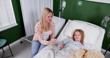 Sevgi dolu ve şefkatli bir anne, hastane odasındaki çocuğuna oyuncak bir ayı hediye ederek büyük neşe verir.