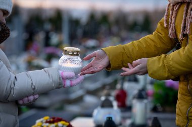Huzurlu bir mezarlıkta, ebedi aşkı ve kaybı sembolize eden bir mumu paylaşmak dokunaklı bir an.