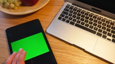 Bilgisayarın yanında yeşil ekranlı tablet bulunan gösterişli bir çalışma alanı, teknolojiye odaklı medya için ideal.