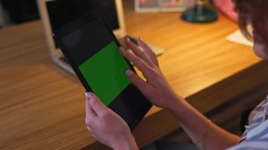Rahat ve cezbedici bir çalışma ortamında, bir kadın parlak yeşil ekranı olan bir tabletle meşgul oluyor.