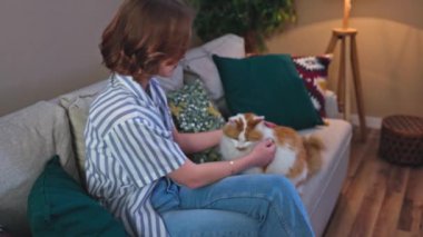 Bir kadın kedisiyle güzel, şık, rahat bir oturma odasında huzurlu ve keyifli bir anın tadını çıkarır.