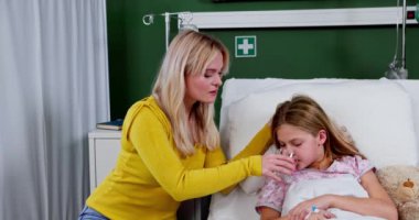 Şefkatli ve kendini adamış bir anne hasta kızına sevgi dolu bir şekilde bakar. Bir hastane yatağında yatarken, ona destek olur.