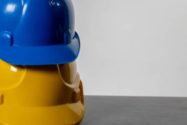 Parlak mavi ve sarı miğferlerden oluşan canlı bir düzenleme. Gri bir yüzeye güzelce istiflenmiş.