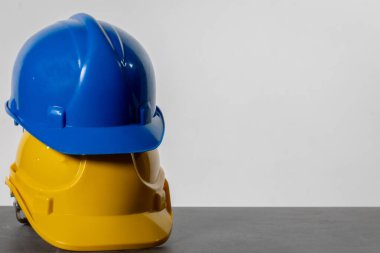 Sade, abartısız bir masada, üst üste dizilmiş iki tane miğfer vardır. Biri mavi, biri sarı.