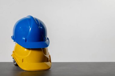 İki parlak renkli güvenlik kaskı, biri mavi ve biri sarı, inşaat alanlarında gelişmiş güvenliği simgeliyor.