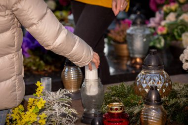 Bir insan, sevdiklerini onurlandırmak için sessiz bir mezarlıkta mum yakar.