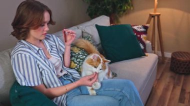 Bir kadın, huzurlu ve huzurlu bir anda sevgili kedisiyle rahat bir oturma odasında keyif alır.