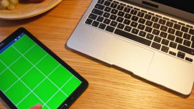 Gelişmiş teknoloji ve verimliliği vurgulayan, el yapımı ahşap bir masada modern bir dizüstü bilgisayar ve şık bir tablet.