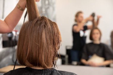 Modern bir salon ortamında, çok yetenekli bir kuaför müşterinin saçı üzerinde özenle çalışır.