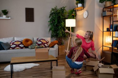 Bir grup kadın, şık ve şık oturma odalarını dekore ederken çeşitli kutuları açıyor.