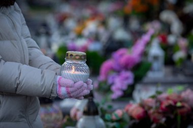 Şu anda, canlı çiçeklerle çevrili huzurlu bir mezarlıkta titreyen bir mum tutuyorum.