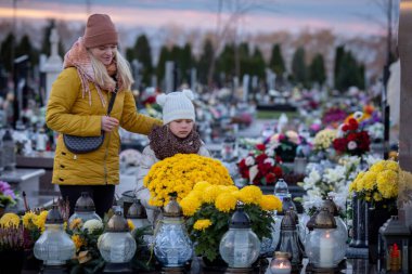 Huzurlu bir mezarlıkta, çiçeklerin arasında bir anne ve çocuğun anısına dokunaklı bir an yaşanıyor.