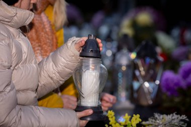 Katılımcılar canlı çiçeklerle çevrili mum ışığı nöbeti sırasında nazikçe baş döndürücü fenerler tutarlar.