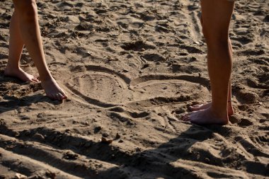 İki farklı ayak izi, sıcak kumsalda karmaşık desenler bırakır. Neşeli ve neşeli bir anı yakalar.