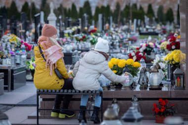 Canlı çiçekler ve içten anılarla süslenmiş huzurlu bir mezarlıkta iki kişi, kaybettikleri sevdiklerini onurlandırır.