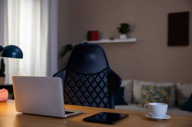 Şık bir ev ofisi, şık bir dizüstü bilgisayar, rahat bir sandalye ve hoş bir atmosfer için sıcak bir ışıklandırma.