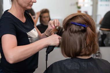 Çok yetenekli bir stilist, çağdaş kuaför ortamındaki bir müşteri için moda saç kesimi ustalıkla hazırlıyor.