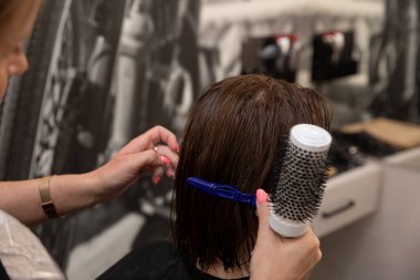 Çok yetenekli bir stilist profesyonel bir kuaför servisi sırasında ıslak saçlarını ustalıkla tarıyor.