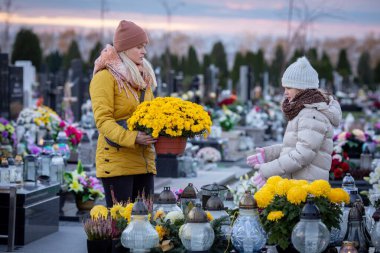 Çiçekler ve parlayan fenerlerle süslenmiş güzel bir mezarlıkta kalpten bir anma anı yaşanıyor.
