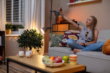 Genç bir kadın şık oturma odasında rahat ve rahat bir akşamın tadını çıkarıyor ve gerçekten huzurlu bir anı yakalıyor.