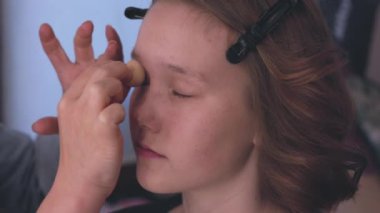 Genç bir kız makyajını güzelce yaptırıyor, göz kamaştırıcı güzelliğini ve sanatını yumuşak ve zarif bir şekilde sergiliyor.