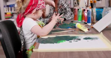 Neşeli bir çocuk, renkli, canlı bir sanat alanında eşsiz bir yaratıcılık sergileyerek, rehberlik ile resim yapar.