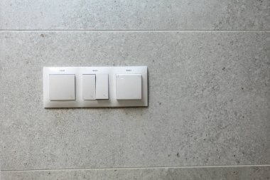 Bu modern bir duvar anahtarı tabağı. Şık, gri bir arkaplana karşı üç zarif düğme sergiliyor.