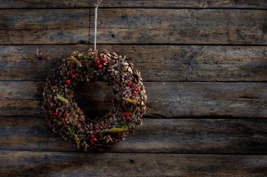 Çok güzel işlenmiş ve tasarlanmış bir çelenk sade ahşap tahtalara asılmış, mevsimlik dekor ve cazibe için mükemmel.