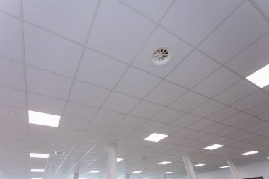 Fayans tasarımı ve optimal aydınlatma için entegre ışıklandırma içeren temiz ve modern bir ofis tavanı.